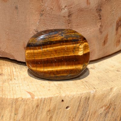 Galet en pierre naturelle polie aux reflets brun et doré posé sur un support en bois