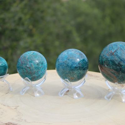 Sphères en apatite bleue polie présentées sur des supports transparents en extérieur